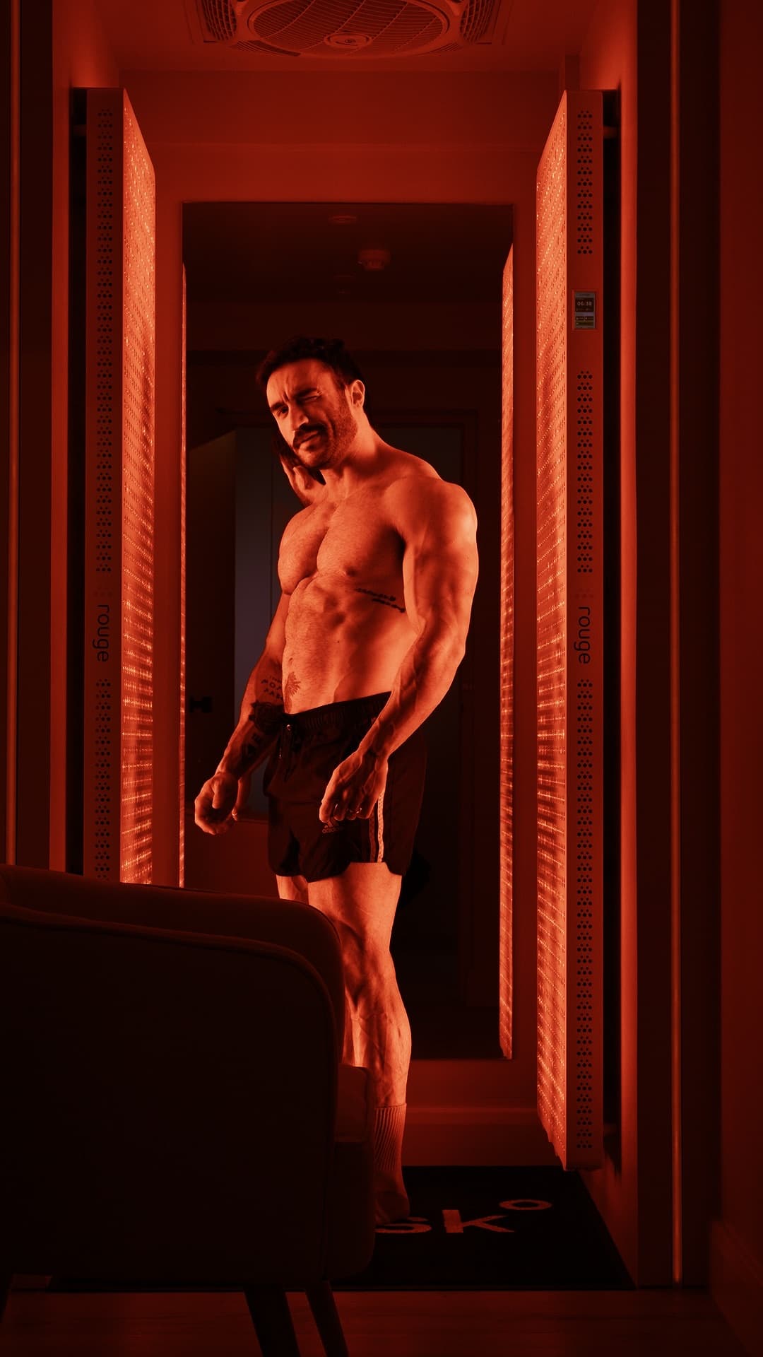 Client standing in whole body red light therapy booth at Brysk